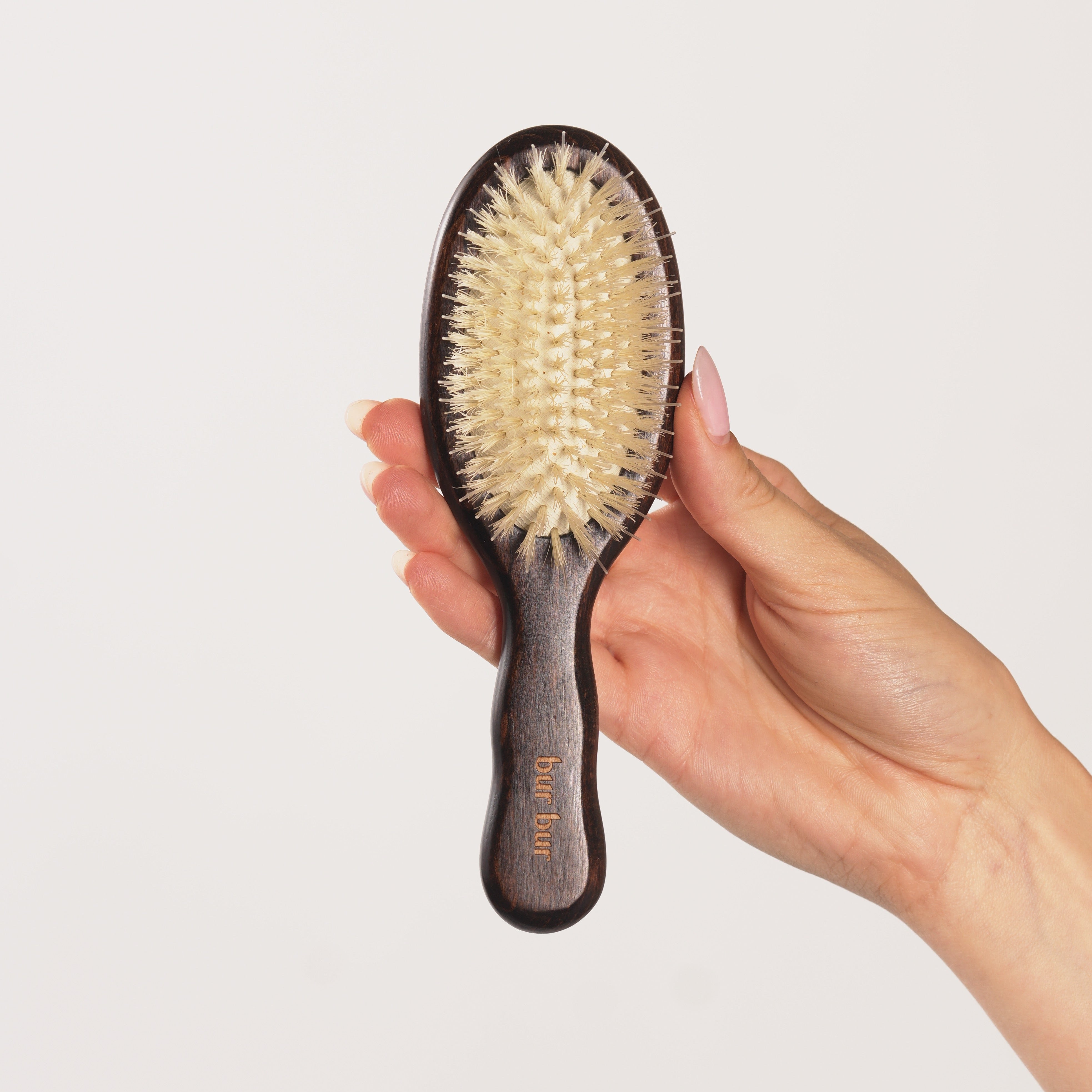 Hand holding a hairbrush against a light background